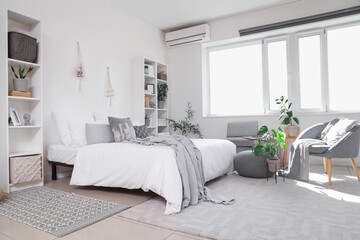 Interior of modern bedroom with shelving units and houseplants