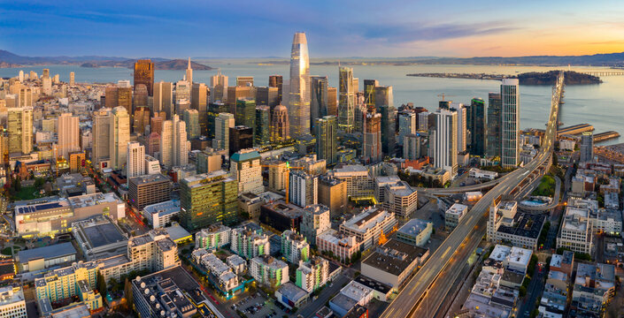 Aerial view of the San Francisco skyline at dusk in California, USA. The photo shows the city's skyscrapers and the Bay Bridge, highlighting urban development.