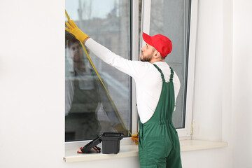 Male worker measuring window in room