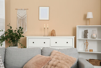 Sofa and chest of drawers with candles in interior of living room