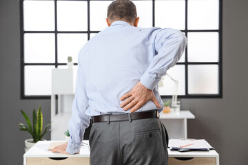 Mature businessman suffering from back pain in office