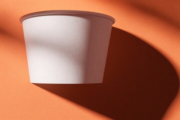 Blank disposable paper cup on orange background