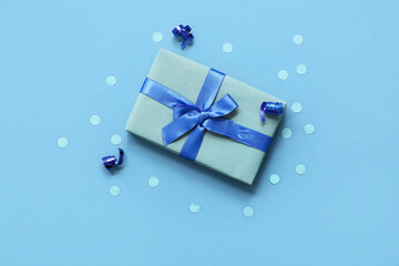 Blue gift box with serpentine and confetti on color background