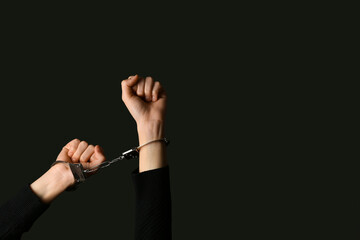 Female hands in handcuffs on black background