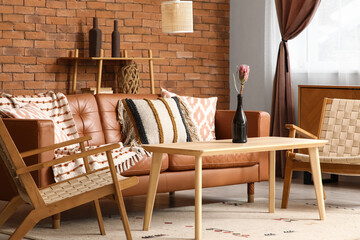 Cozy sofa, wicker armchairs and coffee table in interior of living room