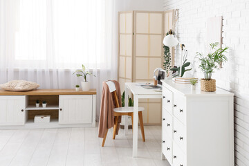Interior of office with workplace, folding screen and plants