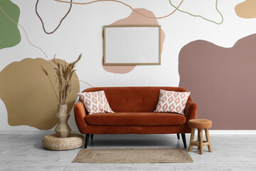Interior of stylish living room with brown sofa, blank frame and pampas grass