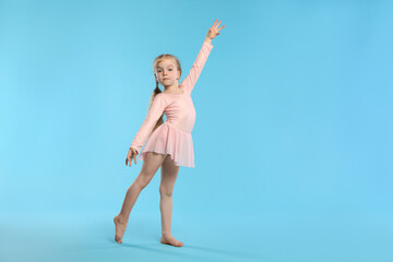 Obraz premium Cute little girl dancing on light blue background, space for text