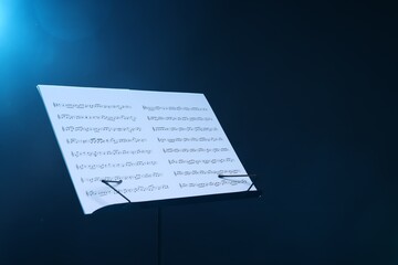 Stand with music sheets on dark blue gradient background, space for text