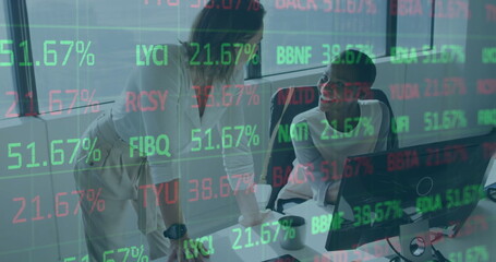 Collaborating colleagues in business attire analyzing market data at office desk, with monitor