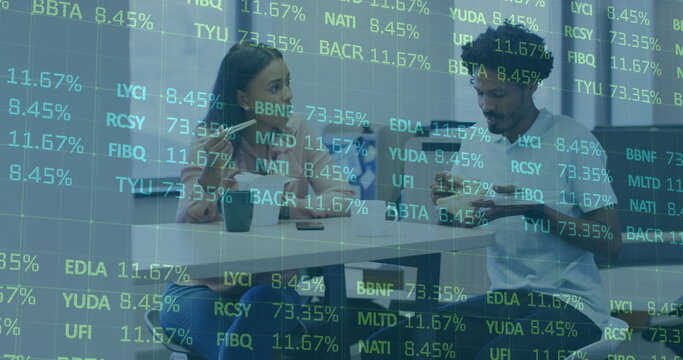 Reviewing digital stock data, two colleagues using smartphone and tablet in meeting room with mugs
