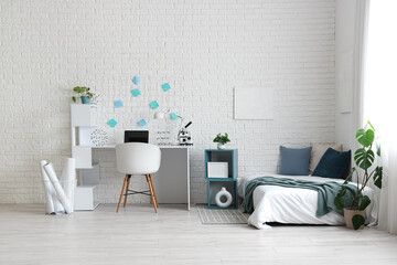 Interior of light teenager's room with bed and workplace