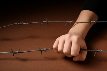 Hand with barbed wire on brown background. Concept of oppression
