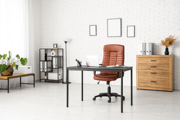 Interior of modern office with workplace, lamp and shelf unit