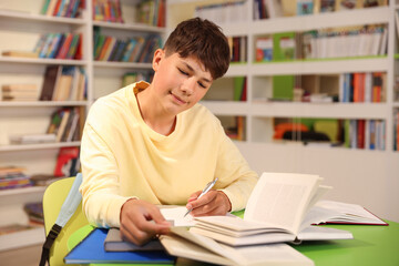 Student with books studying at table in library