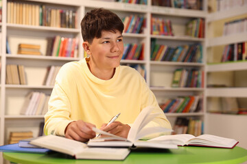 Student with books studying at table in library. Space for text
