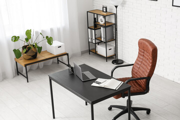Interior of modern office with workplace, lamp and shelf unit