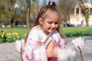 Cute little girl near beautiful tulips outdoors