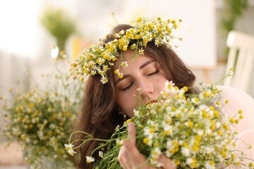 Portrait of beautiful woman with chamomile flowers indoors