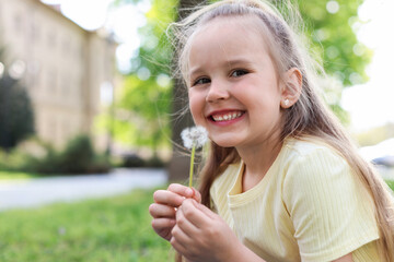 Cute little girl with beautiful dandelion outdoors, space for text