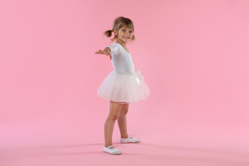 Cute little girl dancing on pink background
