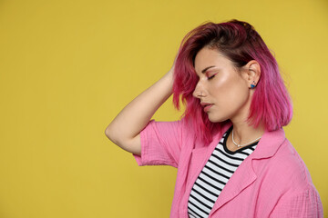 Beautiful woman with pink dyed hair on yellow background, space for text