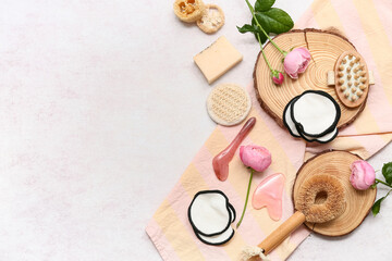 Cotton pads, bath supplies and flowers on light background