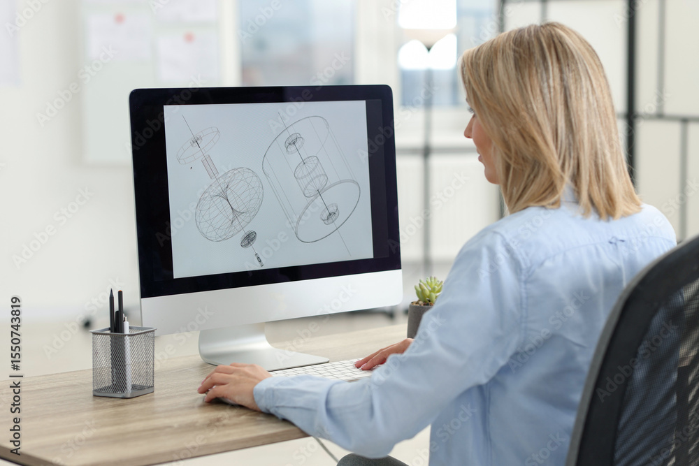 Poster technician making digital engineering drawing on computer at desk in office, back view