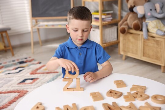 Dyslexia. Little boy learning letters at table indoors - Powered by Adobe
