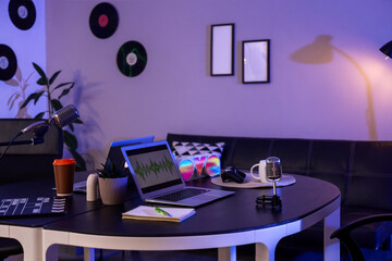 Podcaster's workplace with laptops and microphones in dark studio
