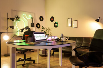 Interior of podcaster's studio with workplace, sofa and glowing lamps
