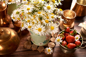 Chamomile flowers and fresh strawberries on wooden table