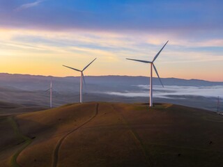 Wind turbines stand tall on rolling hills in Livermore, California, USA, harnessing wind power for...
