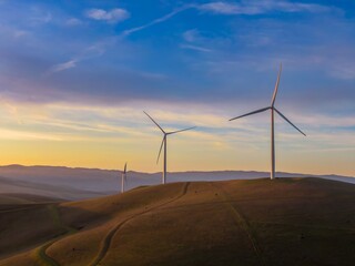 Wind turbines stand tall on rolling hills at sunset in Livermore, California, USA. These windmills...