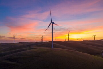 Wind turbines generate clean energy at sunset in Livermore, California, USA.. The wind farm...