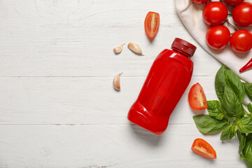 Bottle of tasty ketchup and different ingredients on white wooden background