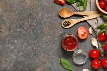 Jar of tasty ketchup and different ingredients on dark background