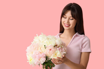 Smiling young woman with peony flowers on pink background