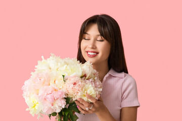 Smiling young woman with peony flowers on pink background