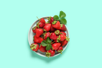 Plate with fresh ripe strawberries on turquoise background