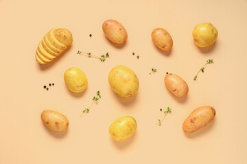 Raw baby potatoes with thyme and peppercorns on beige background