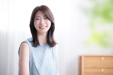 寝起きでベッドに座る女性の上半身　爽やかな朝のイメージ