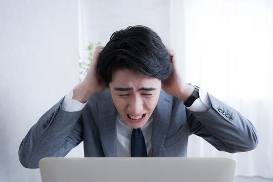 パソコンを見る 仕事で失敗やタスクや納期を忘れて困るビジネスマン　頭を抱える