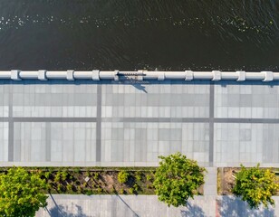 Aerial view of a city promenade with grey stone pavement, trees, and a river. Perfect for backgrounds or urban design projects.