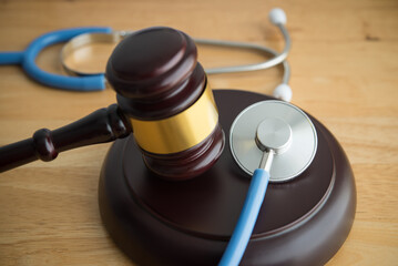 judge hammer gavel and doctor stethoscope on wooden table background in courtroom. Health law, medical law rules, regulations in the health care industry and its patients, medical malpractice concept.