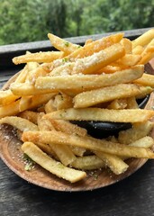 Seasoned French fries with parmesan and herbs on a wooden plate