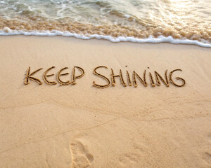 Fototapeta premium Keep shining message written in the sand on a beach with gentle waves approaching