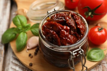Tasty sun dried tomatoes, fresh vegetables and peppercorns on wooden table, closeup