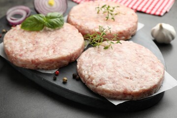 Fresh raw patties for burger and spices on grey table, closeup