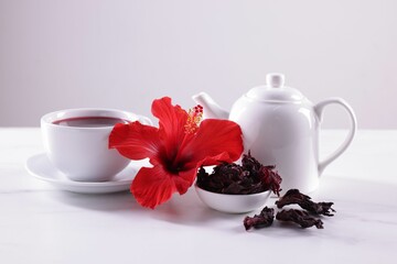Tasty hibiscus tea, dry roselle sepals and beautiful flower on white table against grey background